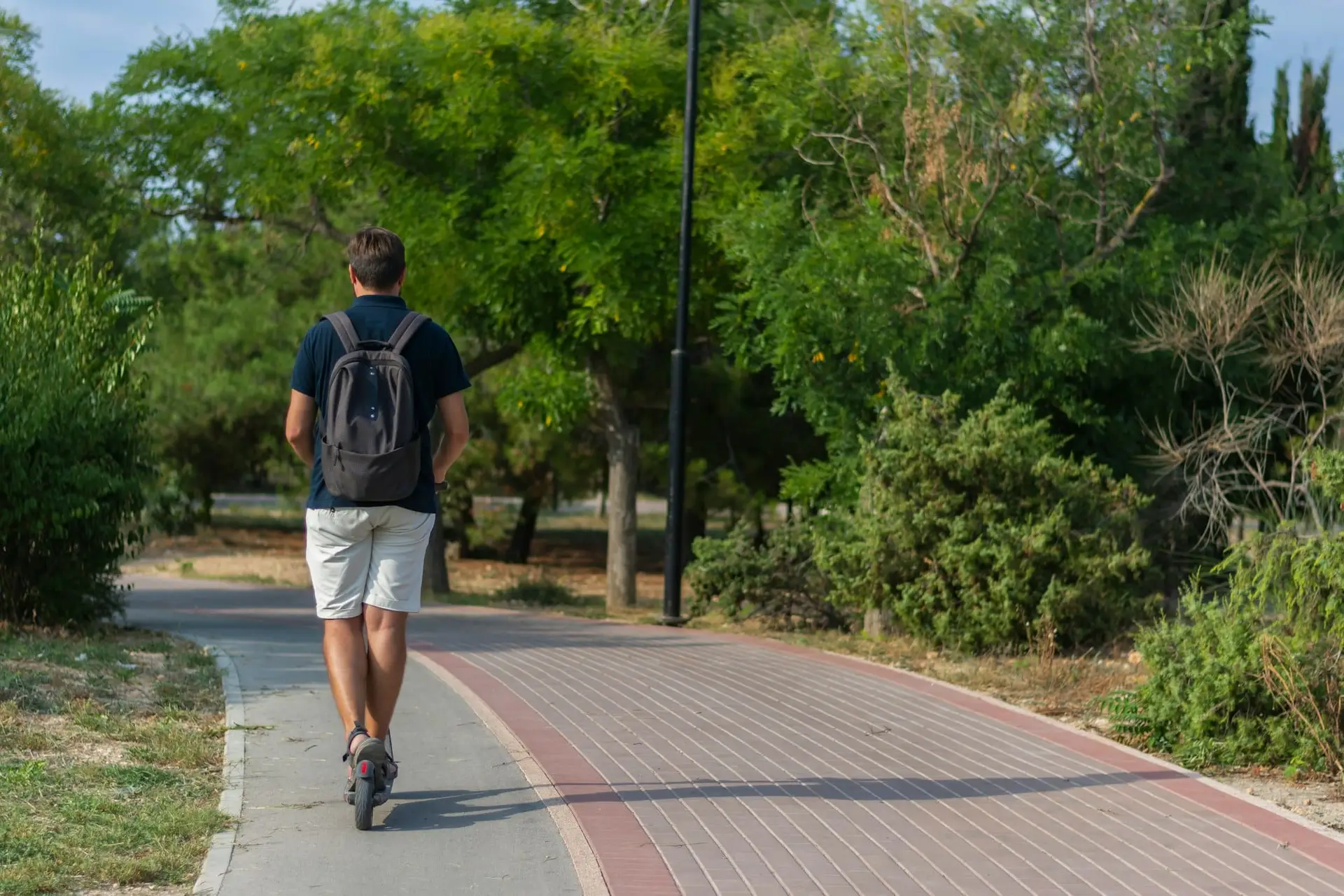 Moderno scooter eléctrico ecológico calentamiento global transporte hombre vista trasera scooter eléctrico
