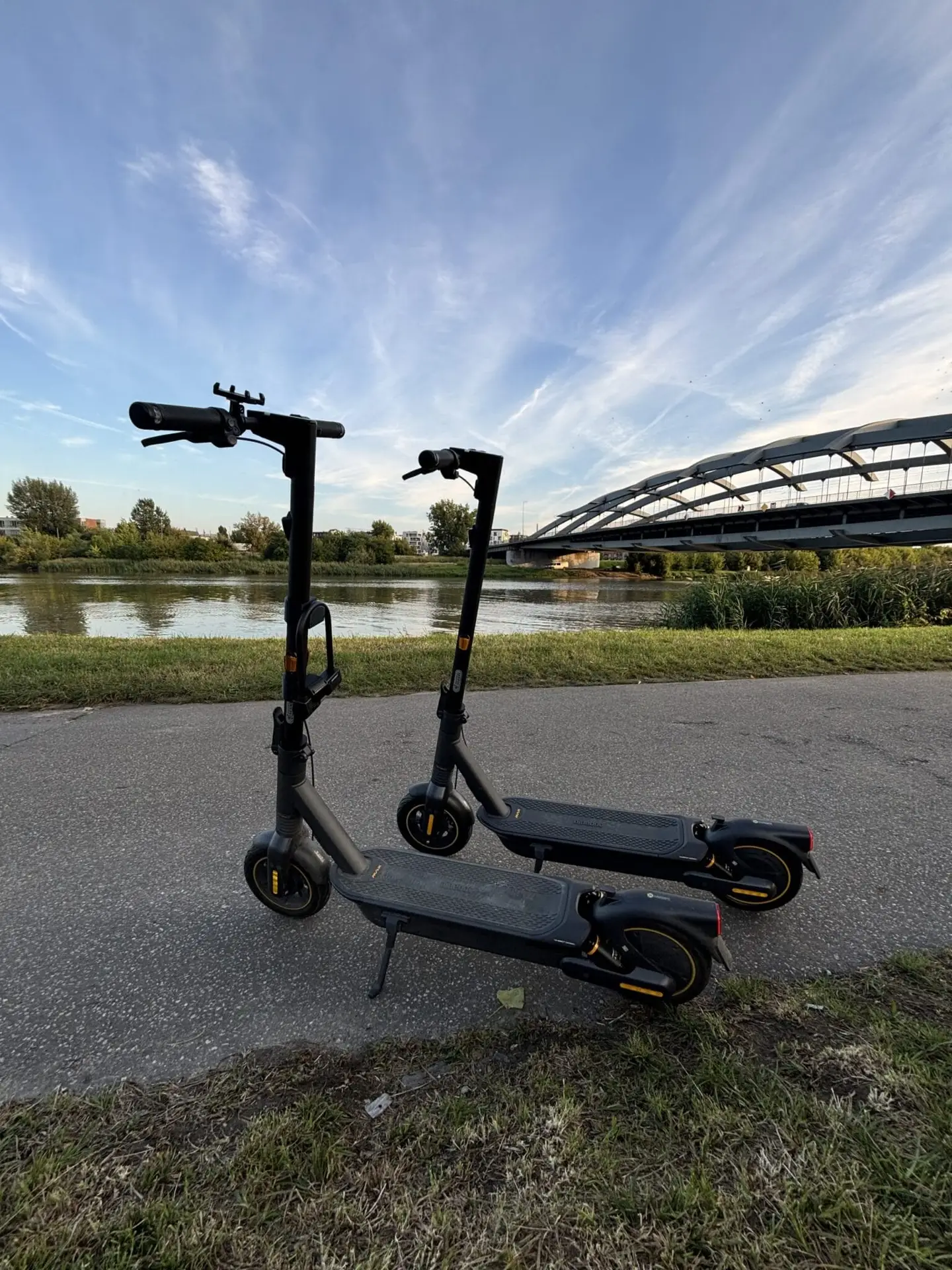 Dos scooters eléctricos aparcados con el río Vístula como telón de fondo - City Glide en Cracovia